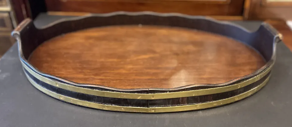 6. Hardwood oval tray with wavy edged border gallery and two brass bounds and carved handles