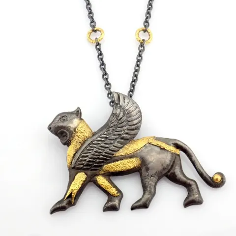 A mythological object intricately engraved in silver with gold  accents