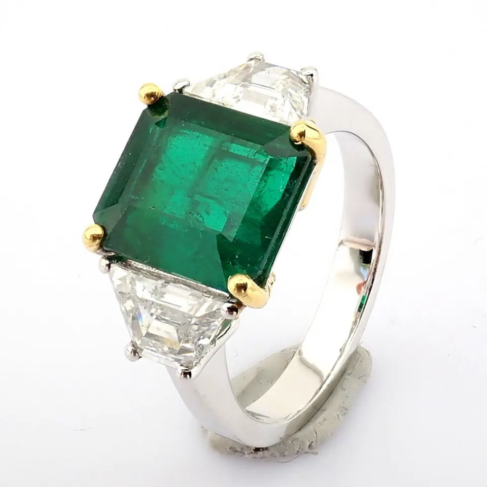 A luxurious 18k white gold ring detailed with vibrand 3.29 ct emerald and 1.16 ct brilliant diamonds