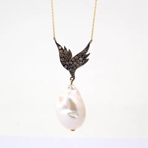 An exquisite wing necklace detailed with baroque pearl , brilliant diamonds and gold on silver.