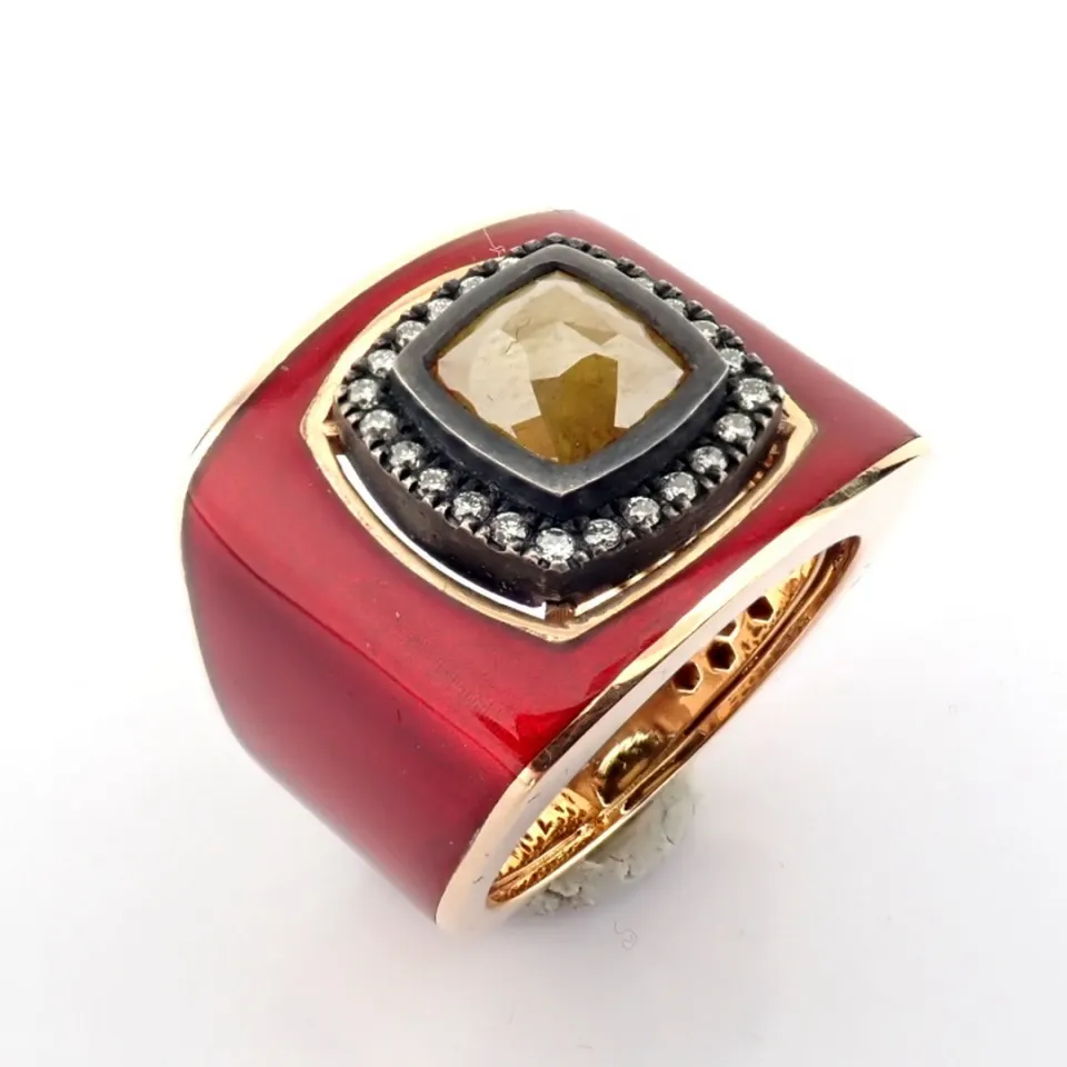 A luxurious gold ring featuring red laser enamel, elegantly adorned with  brilliant diamonds