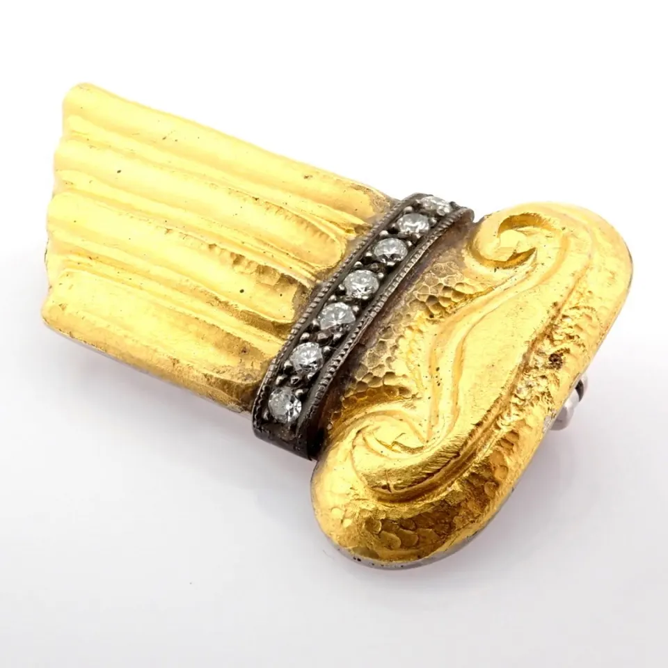 A mythological object brooch engraved in 24-carat goldwith silver accents and  diamonds