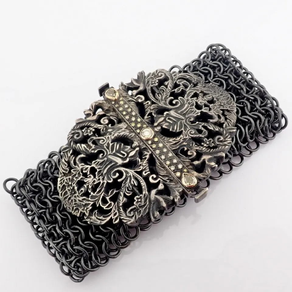 A handwoven silver bracelet adorned with gold and precious stones