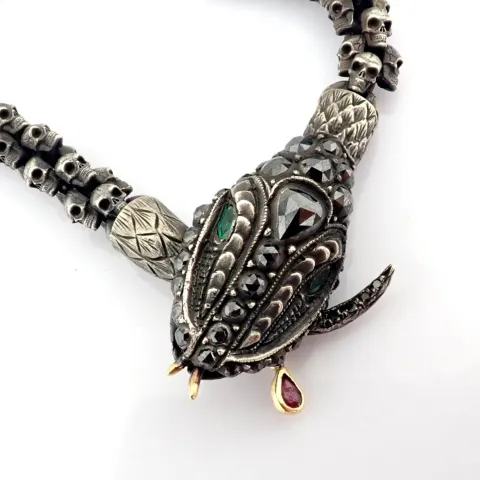 An exquisite snake necklace intricately detailed with skulls on chain.brilliant diamonds in silver