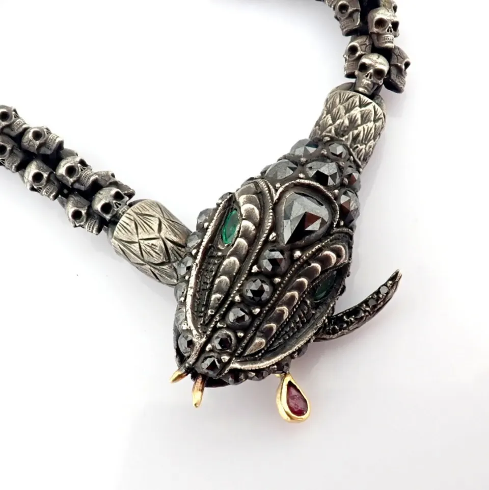 An exquisite snake necklace intricately detailed with skulls on chain.brilliant diamonds in silver