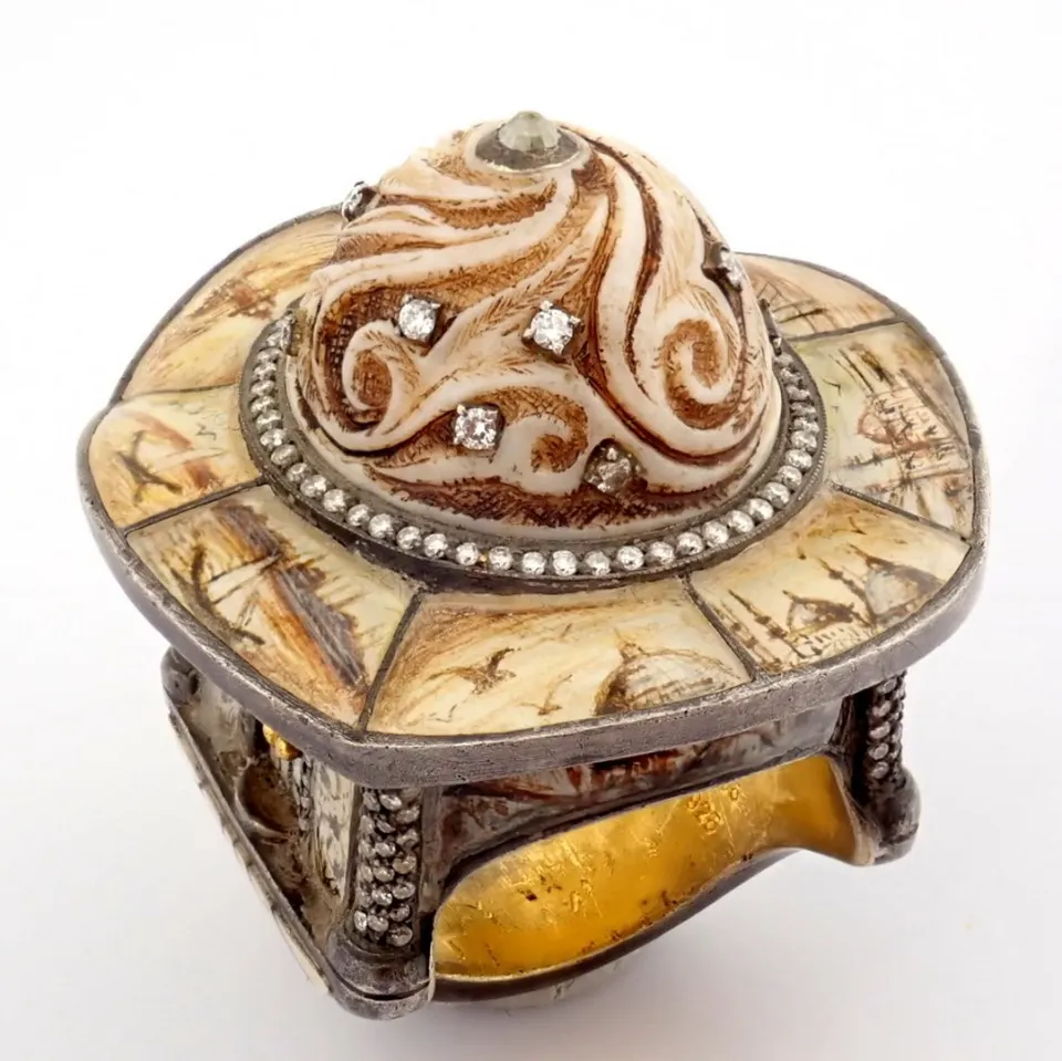 An exquisite gold/silver ring detailed with bone, carved center surrounded by micro art and diamonds