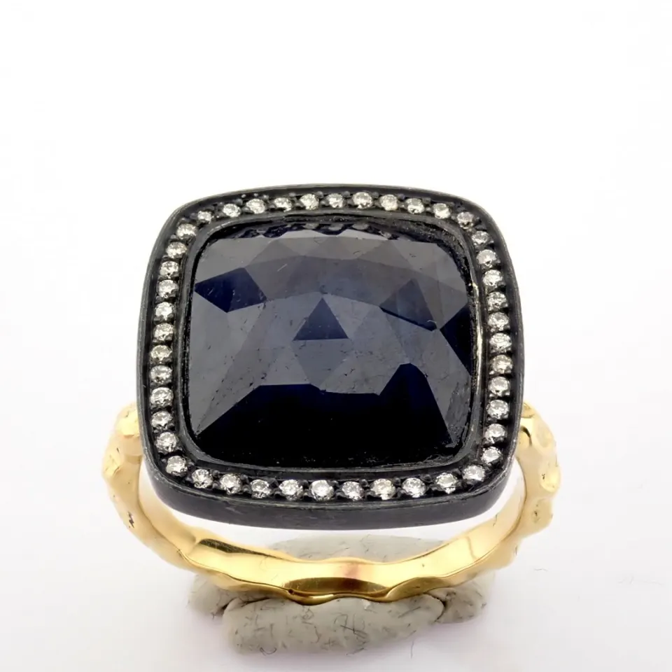 Gold ring detailed with slice cut rough sapphire in the center, brilliant diamonds on silver frame