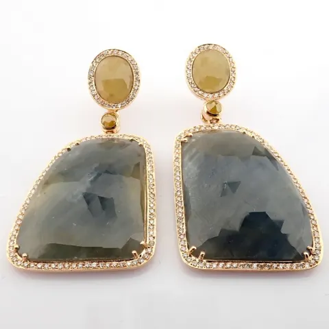 Gold earrings detailed with slice cut rough sapphire in the center and brilliant diamonds on frame